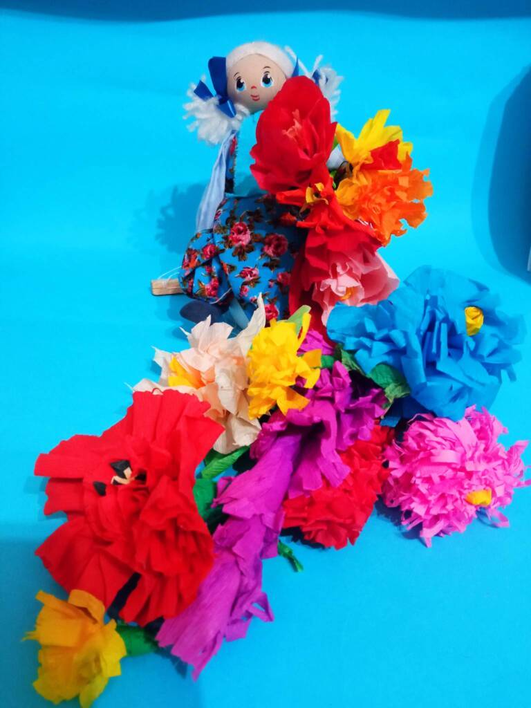 kwiaty wykonane z bibuły położone na niebieskim papierze